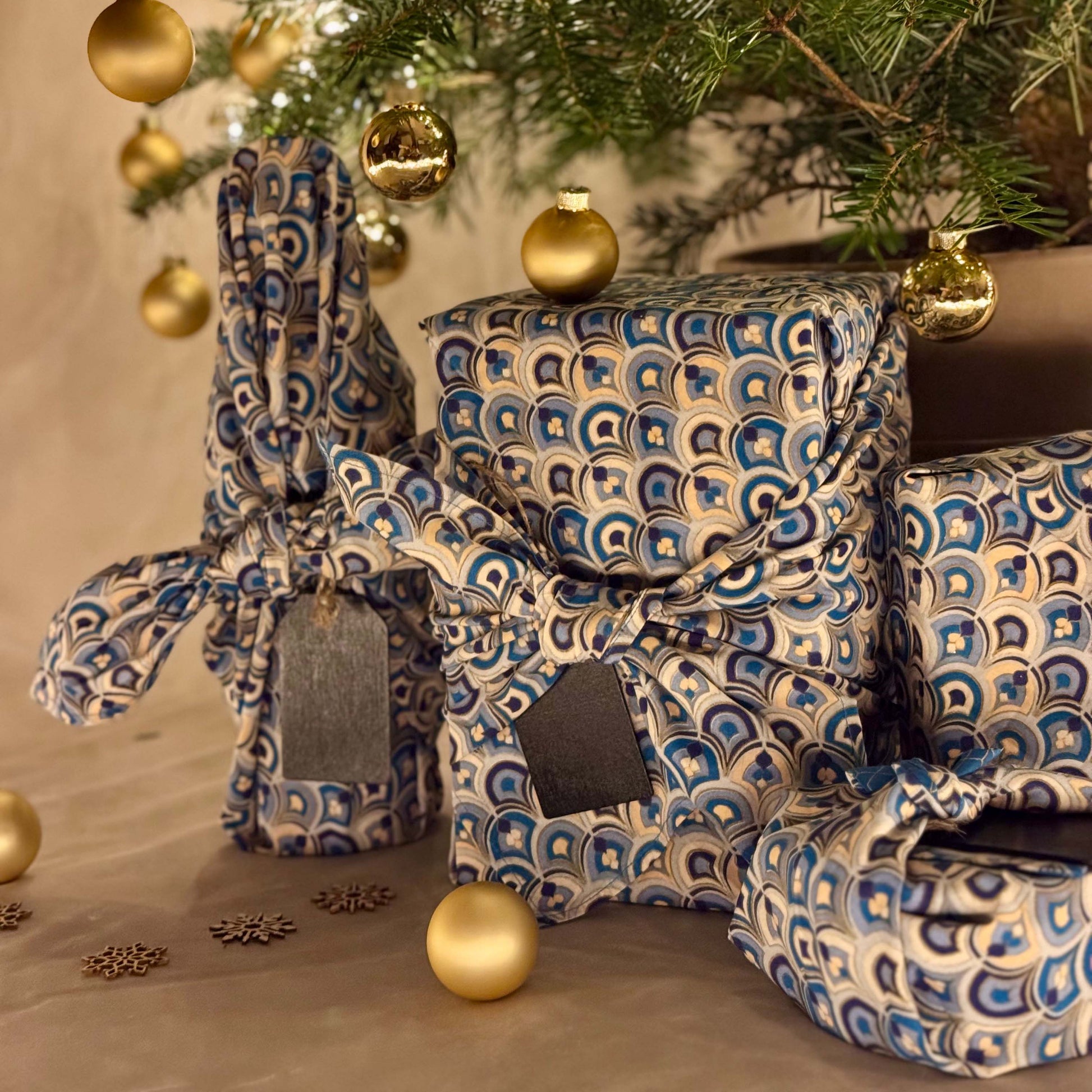 Decorative boxes with blue and white pattern under a Christmas tree with gold ornaments.